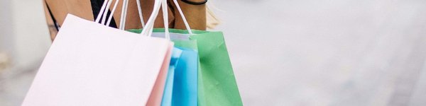 Shopping image with a female person holding several colored paper bags.